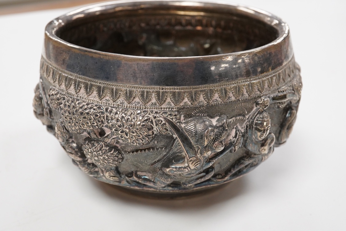 A late 19th/early 20th century Burmese white metal bowl, embossed with figures and animals in continuous battle scene, top diameter 12.4cm.